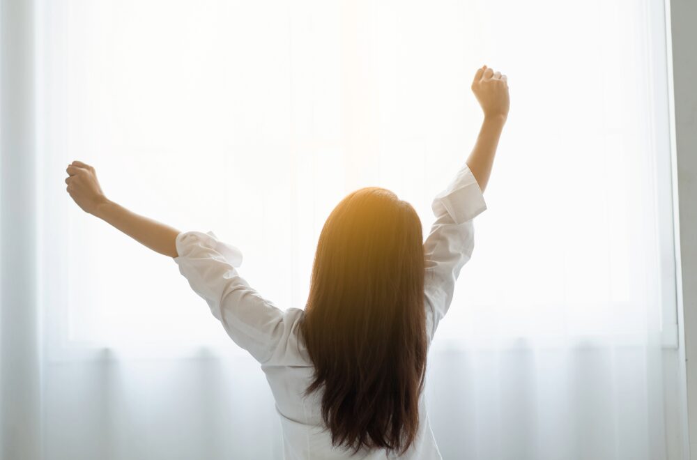 日差しを浴びながら伸びをしている女性