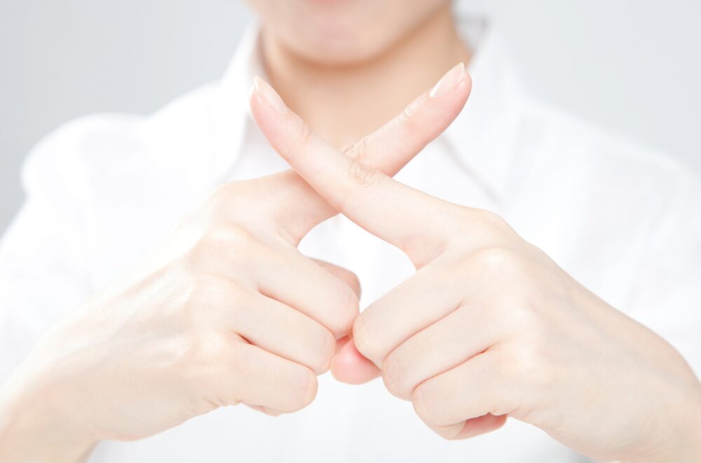 両手で×のサインをしている写真