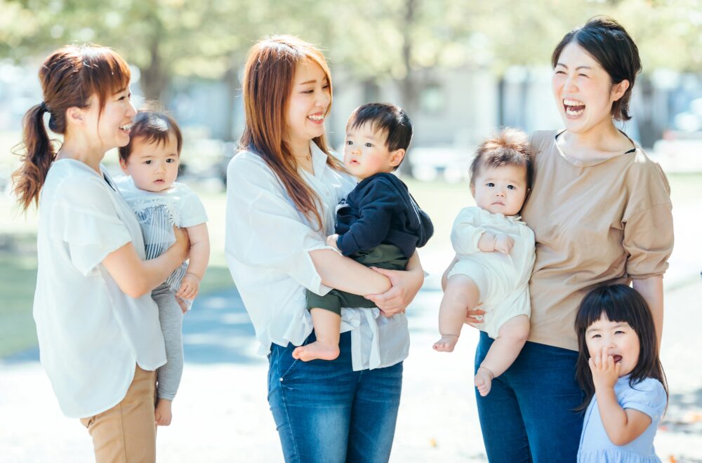 小さい子供を抱っこしながら談笑するママ3人