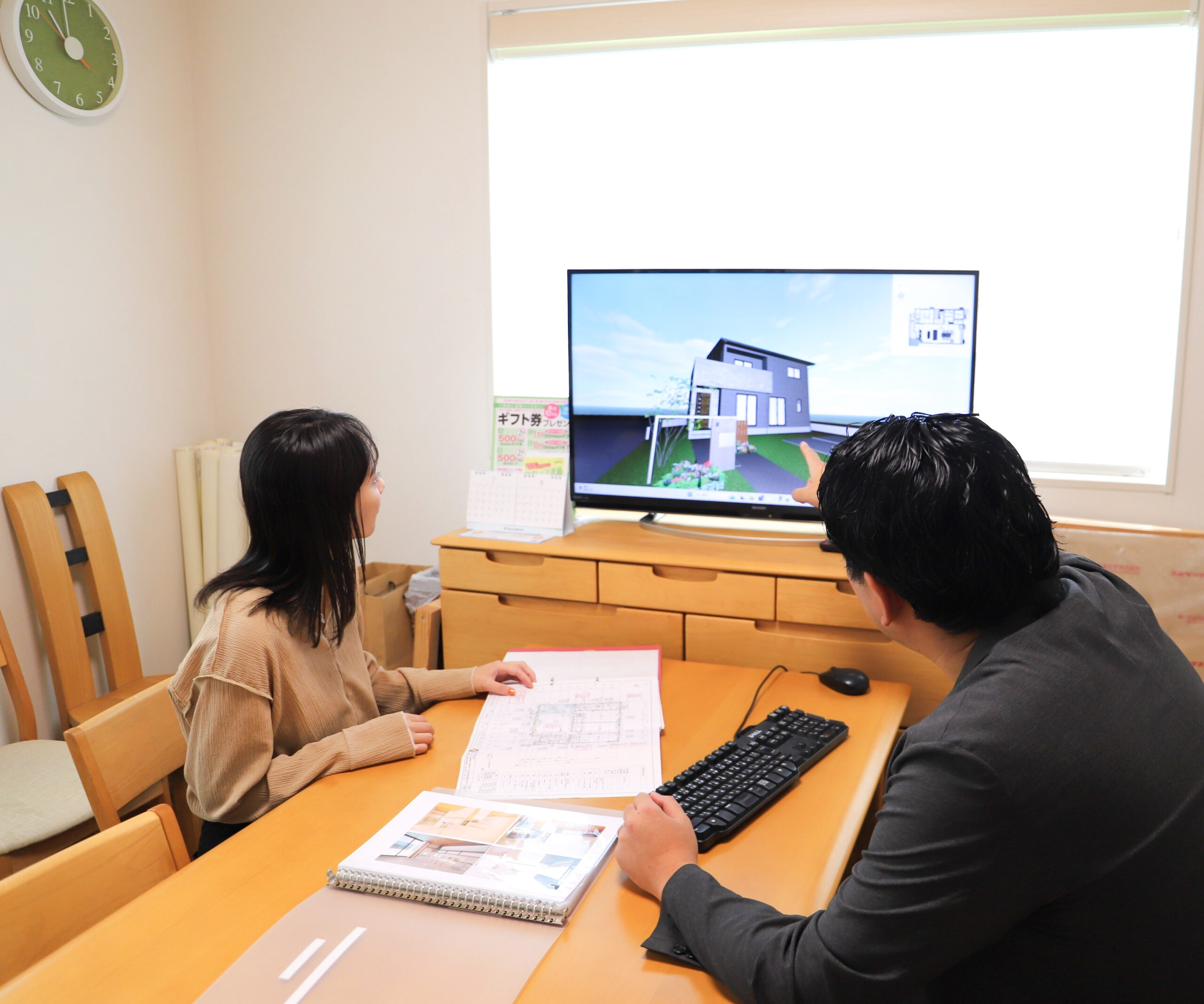 営業スタッフとパソコンを見ながら住宅の打ち合わせをする様子
