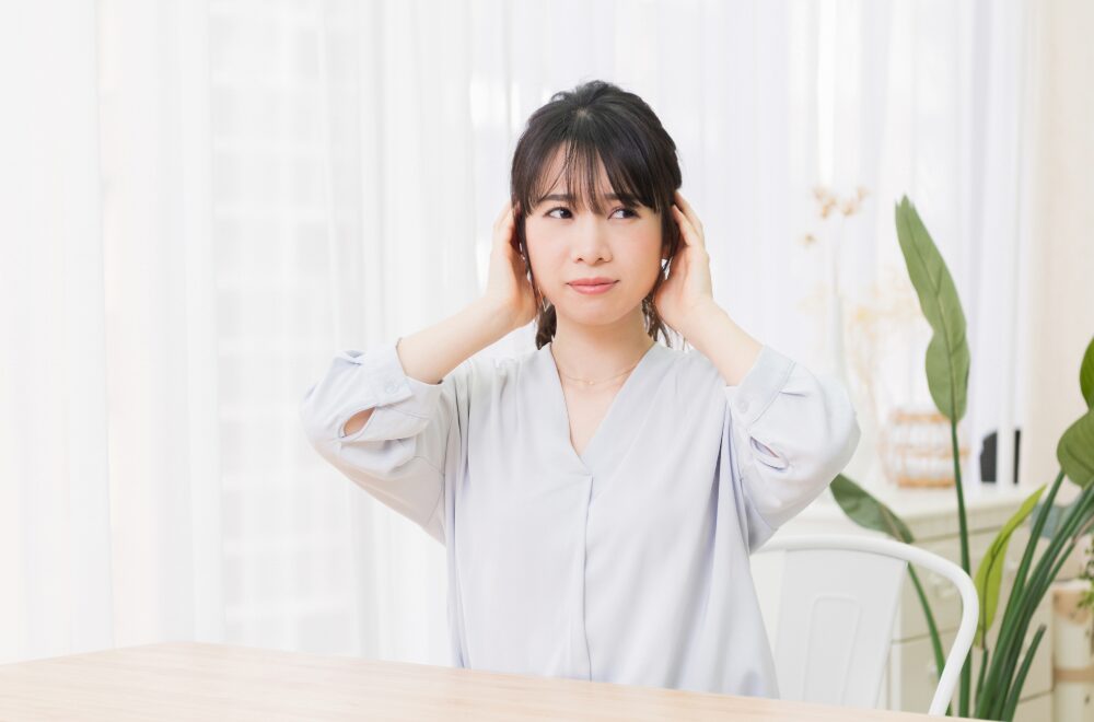 耳をふさいで困っている女性
