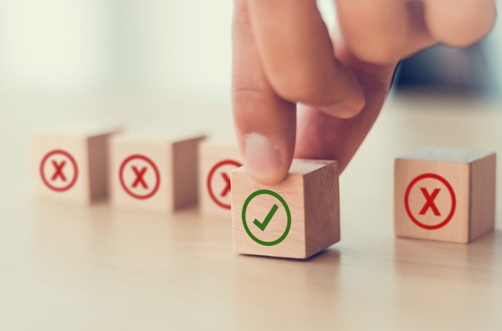 ×とチェックマークがかかれた積み木を持つ手